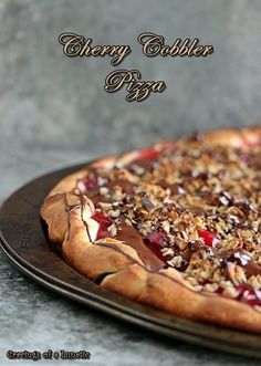 a cherry cobbler pizza with pecans and chocolate toppings on a metal platter