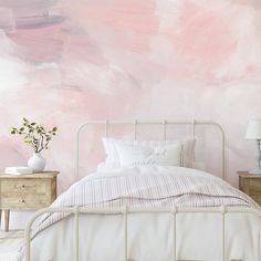 a bedroom with pink and white paint on the walls, bedding and nightstands