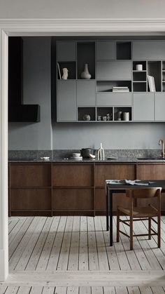 an open door leading to a kitchen with wooden floors and cabinets in grey, black and white colors