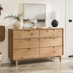 a wooden dresser sitting in a living room next to a wall mounted clock and potted plant