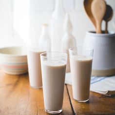 three glasses filled with milk sitting on top of a wooden table