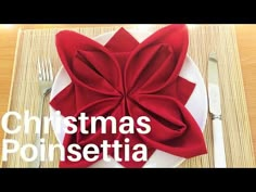 a white plate topped with a red bow on top of a wooden table next to silverware