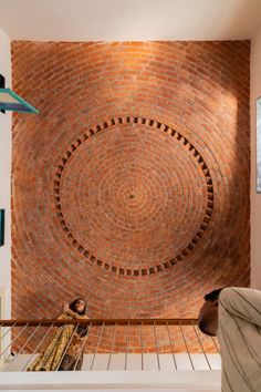 a person sitting on a bench in front of a brick wall with a circular design