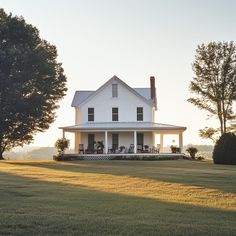 a large white house sitting on top of a lush green field