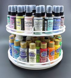 several different colors of acrylic paint are arranged on a three tiered rack