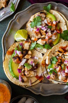 three tacos with chicken, onions and cilantro on a silver platter