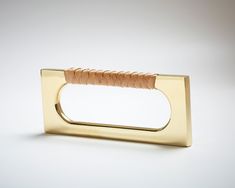 a gold napkin holder with a leather handle on a white surface, in the shape of a rectangle