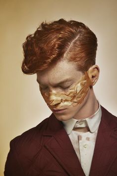 a man in a suit and tie with gold foil on his face is looking down