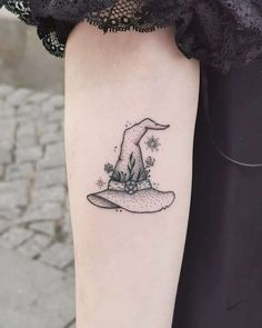 a woman's arm with a small wizard hat tattoo on the left inner forearm