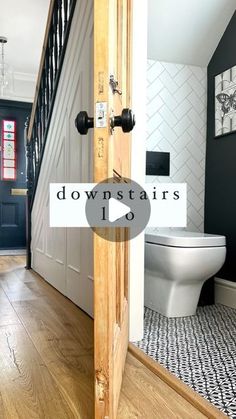 an open door leading to a bathroom with black and white tile on the floor, and stairs in the background