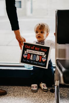 a little boy sitting on the ground holding up a sign that says out of my way i'm telling to my daddy for this first time today