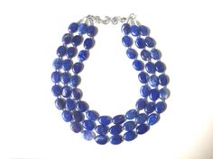 "A great statement piece! Three of layers of royal blue oval Beads that are hand made and swirled so no 2 beads are exactly alike. Each acrylic bead is spaced with a small silver bead to give this a polished look! Approximately 17 inches at shortest strand, with a 4 inch chain and silver plated lobster clasp.I can also make this in a single strand for $13.90. Convo me! Earrings are 1.25\" drop. These make great, affordable bridesmaid necklaces for weddings as well. Ask me about bulk discounts! N Blue Gemstone Beads Necklaces For Party, Blue Gemstone Beads Necklace For Party, Blue Wedding Bridesmaid, Blue Multi-strand Beaded Necklace For Gift, Dark Blue Necklace, Blue Multi-strand Beaded Necklace, Bridesmaid Necklaces, Blue Multi-strand Necklace With Large Beads, Artisan Multi-strand Blue Necklaces