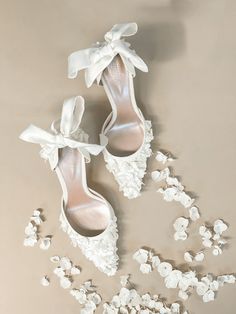 two pairs of white shoes with bows on them next to popcorn flakes in the air