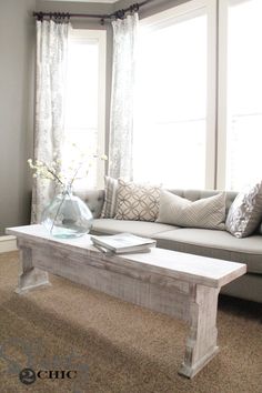 a living room with a couch, coffee table and window sill in the corner