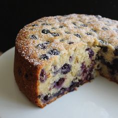 a blueberry cake on a plate with one slice cut out