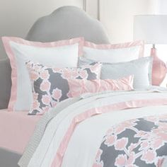 a bed with pink and gray comforters in a bedroom