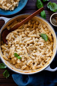 macaroni and cheese in a skillet with wooden spoons on the side