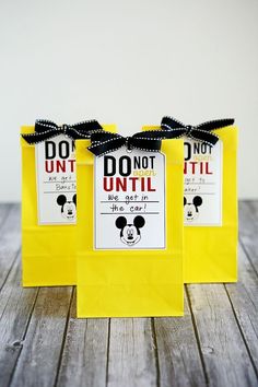 three yellow bags with mickey mouse tags on them, one has a black bow and the other has a white polka dot