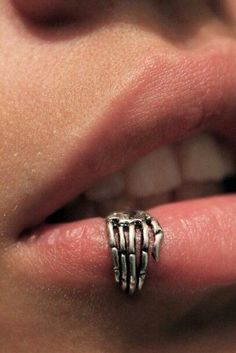 a close up of a person's mouth with a ring on their finger and teeth