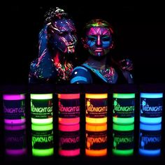 two people standing next to each other with neon paint on their faces and hands in front of them