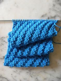 a pair of blue knitted cloths sitting on top of a marble countertop