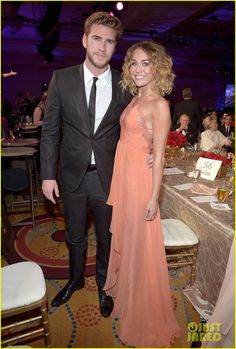 a man and woman standing next to each other in front of a table with cake on it