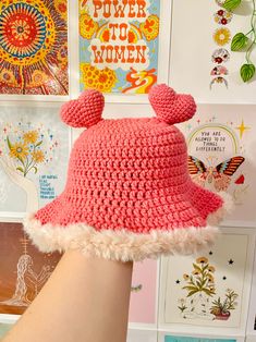 a woman's hand wearing a pink crocheted hat