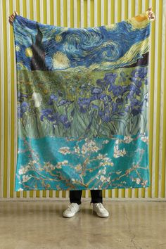 a person holding up a large tapestry with the painting's starry night on it