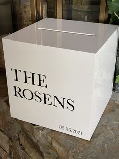 a white box sitting on top of a stone wall next to a potted plant