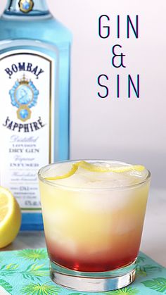 a gin and sin cocktail in front of a bottle with lemon wedges on the side