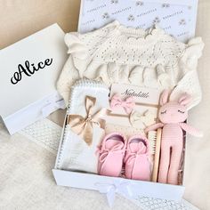 a box filled with pink baby shoes next to a card and some other items in it