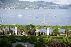 a view of the water and boats from an outdoor garden with hedges in front of it