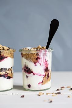 two jars filled with yogurt and granola on top of a white table