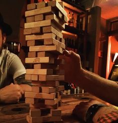 two men sitting at a table with wooden blocks stacked on top of eachother