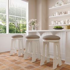 three white stools sitting in front of a counter