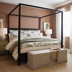 a bedroom with a four poster bed and beige walls