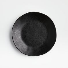 a black plate with speckles on it sitting on a white tableclothed surface