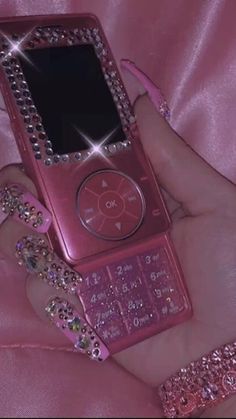 a person holding a pink cell phone with lots of bling on it's screen