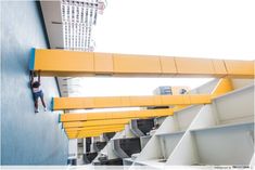 a man climbing up the side of a building on a yellow and white structure with stairs