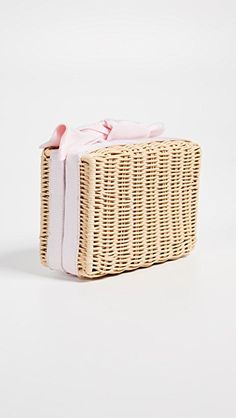 a wicker box with a pink bow on it's lid sitting on a white surface