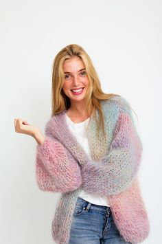 a woman is smiling and holding her arms out in front of the camera while wearing a multicolored cardigan