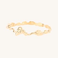 a gold ring with wavy design on the side and small waves in the middle, against a white background