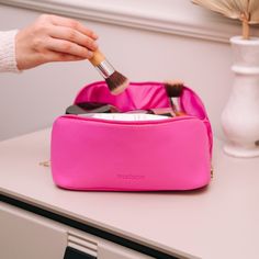 a person is holding a brush in a pink bag on top of a white table