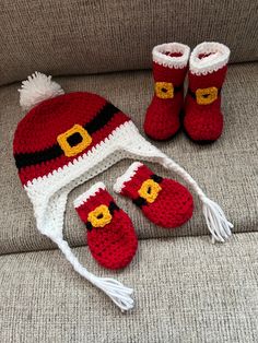 a crocheted hat, booties and mittens are sitting on a couch