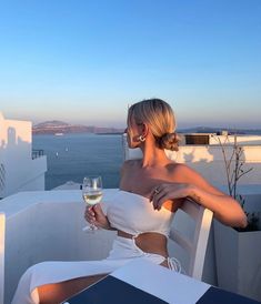 a woman sitting at a table with a glass of wine