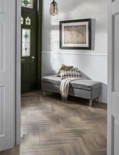 a living room with wood flooring and a gray couch next to a green door