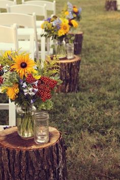 flowers in vases sitting on top of wooden stumps