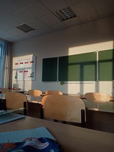 an empty classroom with desks and chairs in front of a window that has the sun shining on it