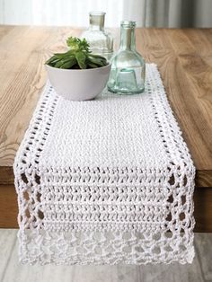 a crocheted table runner with a bowl of succulents on it