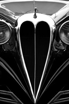 the front end of an old fashioned car with chrome grills and headlights in black and white